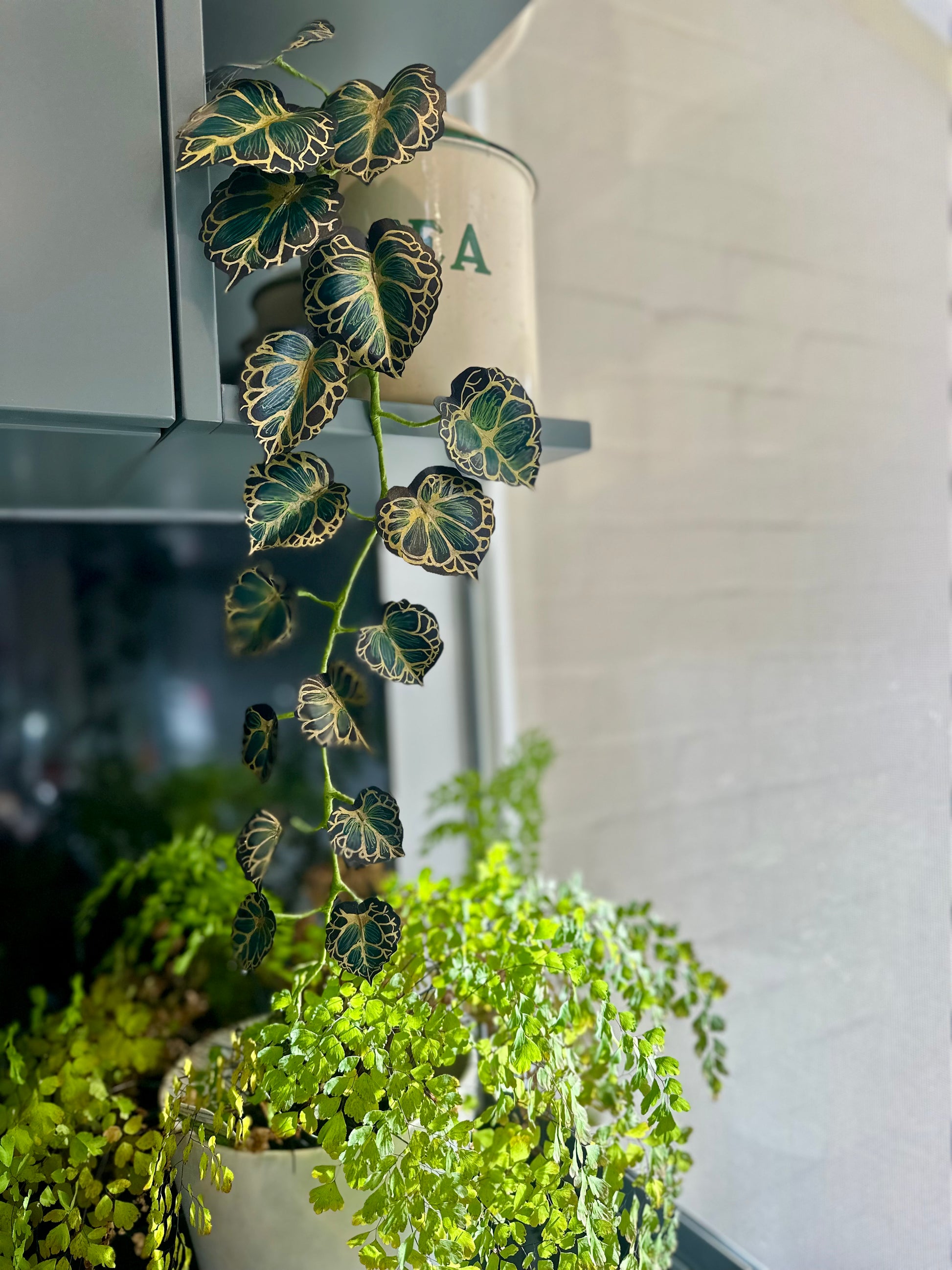 Potted paper plant with decorative painted and handdrawn leaves in a home setting